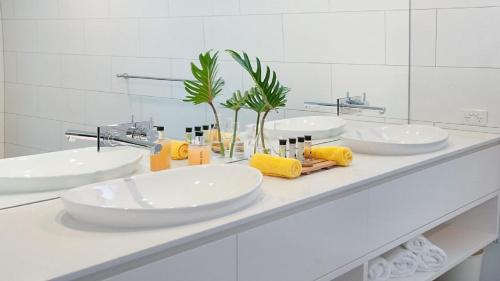 a white bathroom with three sinks and a mirror at Vista in Lennox Head