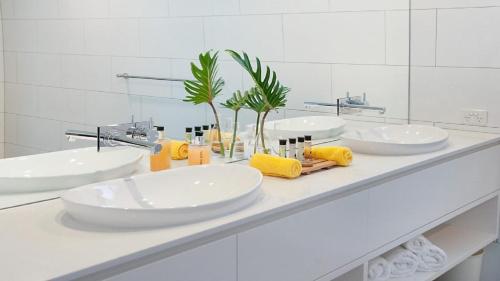 a white bathroom with three sinks and a mirror at Vista in Lennox Head