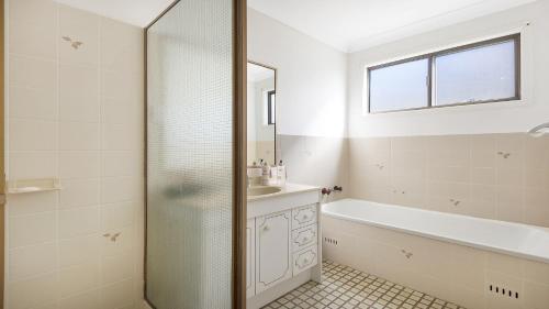 a bathroom with a shower and a sink and a tub at Bailey's Beach House in East Ballina