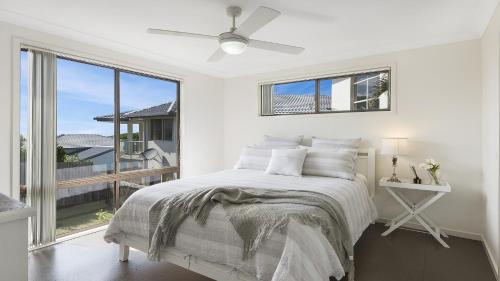 a white bedroom with a bed and a window at Bailey's Beach House in East Ballina