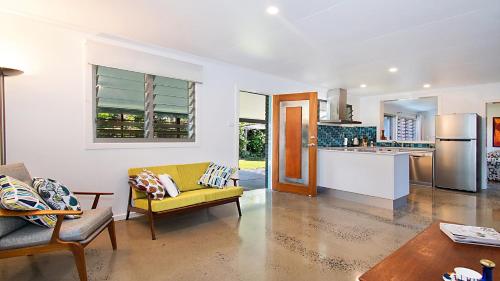 a living room with a yellow couch and a kitchen at Betty's in Lennox Head