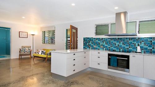 a kitchen with white cabinets and blue tile on the wall at Betty's in Lennox Head