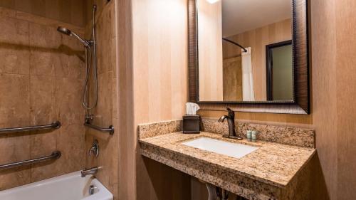 ein Badezimmer mit einem Waschbecken, einem Spiegel und einer Badewanne in der Unterkunft Best Western Newberry Station in La Pine