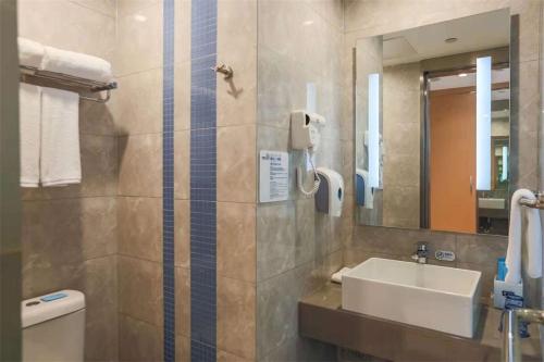 ein Badezimmer mit einem Waschbecken, einem Spiegel und einem WC in der Unterkunft Holiday Inn Express Chengdu Xindu, an IHG Hotel in Chengdu