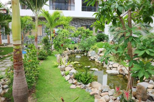 a garden with a pond in front of a building at My Ca Hotel in Cam Ranh