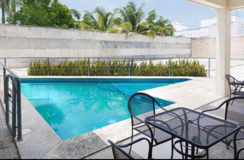 a swimming pool with chairs and a table at Suites Real Tabasco in Villahermosa