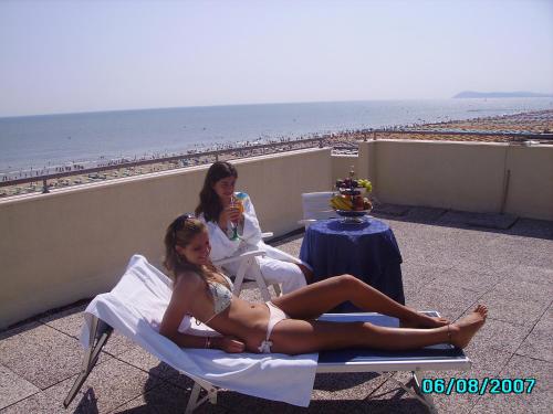 two women in bathing suits sitting on chairs on the beach at Hotel San Francisco Spiaggia in Rimini