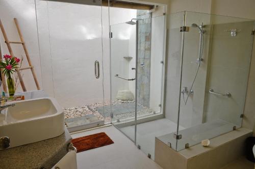 a bathroom with a shower and a sink and a glass shower stall at Punta Bulata White Beach Resort & Spa in Sipalay