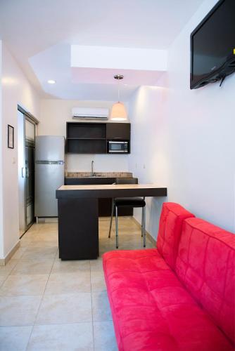 a living room with a red couch and a kitchen at Suites Real Tabasco in Villahermosa