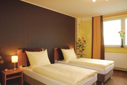 two beds in a hotel room with a window at Hotel Rosenhof in Isenbüttel