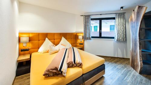 a bedroom with a yellow bed and a window at Biwak Appartements in Sankt Anton am Arlberg