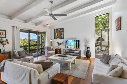 a living room with white furniture and a ceiling fan at Noosa Rest in Noosa Heads