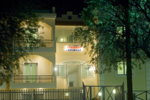 a large white building with a neon sign on it at Garifalo Apartments in Kalyves