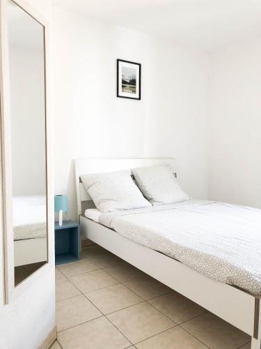 une chambre blanche avec un lit et un miroir dans l'établissement Arson Riquier Port, à Nice