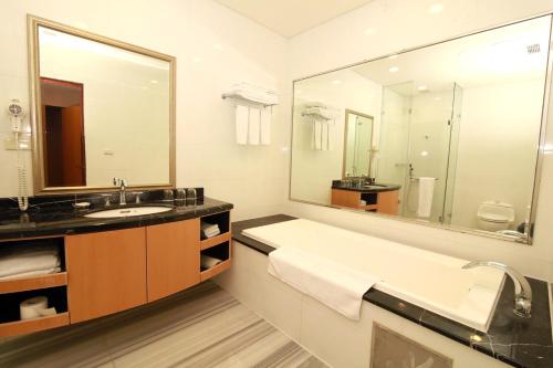 a bathroom with a large sink and a large mirror at Queena Plaza Hotel in Yongkang