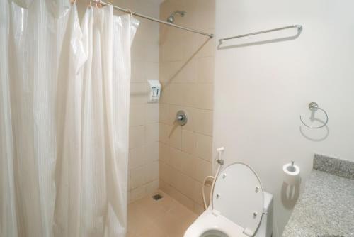 a bathroom with a white shower curtain and a toilet at LeGreen Suite Pejompongan in Jakarta