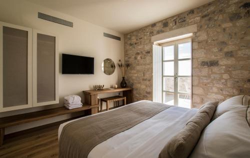 a bedroom with a large bed and a television at BASSA MAINA Villas & Suites in Areopolis