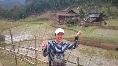 a woman standing on a fence in the rain at Mai Chau Xanh Bungalow in Mai Chau