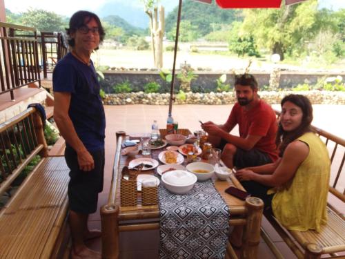 a group of people sitting around a table on a porch at Mai Chau Xanh Bungalow in Mai Chau