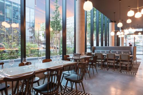 un restaurant avec des tables, des chaises et des fenêtres dans l'établissement The Originals Boutique, Hôtel Maison Montmartre Paris Les Puces, à Paris