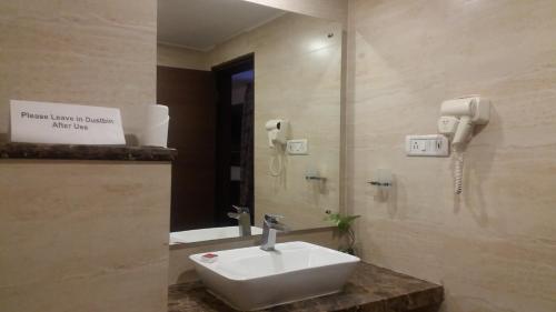 baño con lavabo, espejo y teléfono en Hotel Pai Vista en Mysore