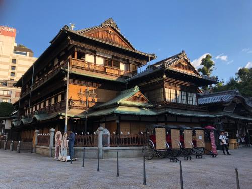 a large wooden building with people standing in front of it at Hotel Patio Dogo in Matsuyama