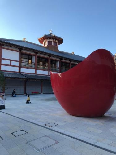 a large red sculpture in front of a building at Hotel Patio Dogo in Matsuyama