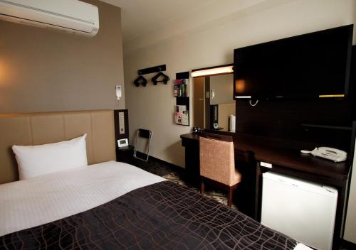 a hotel room with a bed and a desk and a television at APA Hotel Miyazaki-eki Tachibana-dori in Miyazaki