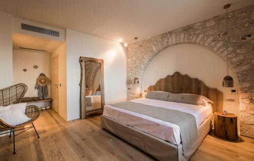 a bedroom with a large bed and a stone wall at BASSA MAINA Villas & Suites in Areopolis