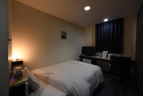 a hospital room with a bed and a desk and a window at R Hotels Inn Hokkaido Asahikawa in Asahikawa