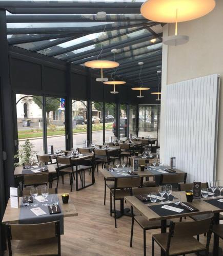 un restaurant avec des tables et des chaises en bois et des fenêtres dans l'établissement Hôtel de la Gare - Restaurant Bistro Quai, à La Roche-sur-Yon