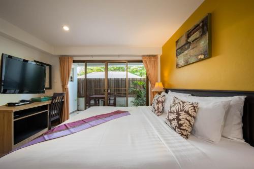a bedroom with a large white bed with a flat screen tv at Kamala Beachfront Apartment in Kamala Beach