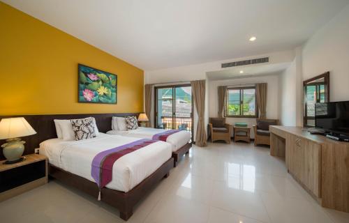 a bedroom with two beds and a flat screen tv at Kamala Beachfront Apartment in Kamala Beach