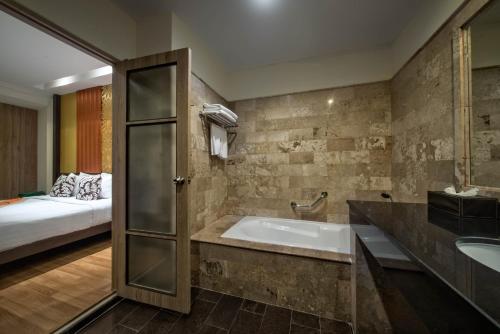 a bathroom with a tub and a bed in a room at Kamala Beachfront Apartment in Kamala Beach