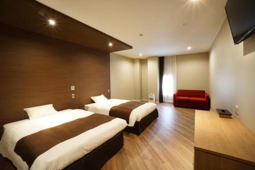 um quarto de hotel com duas camas e um sofá vermelho em Hotel Abest Grande Okayama em Okayama