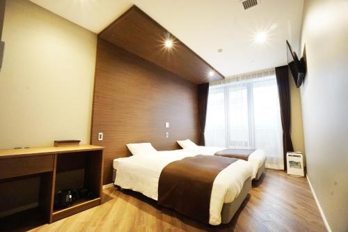 a hotel room with two beds and a window at Hotel Abest Grande Okayama in Okayama