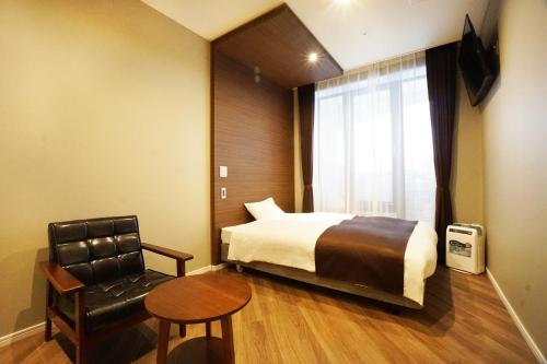 a hotel room with a bed and a chair at Hotel Abest Grande Okayama in Okayama