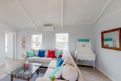 a living room with a white couch with colorful pillows at Midtown Paradise on the Beach in Galveston
