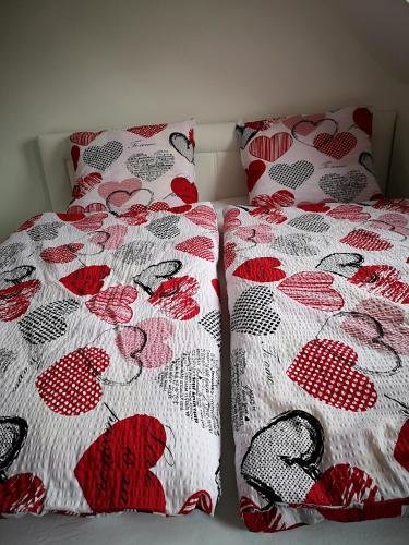 two beds with red and white comforters on them at Centrum Apartman LEYLA in Bardejov