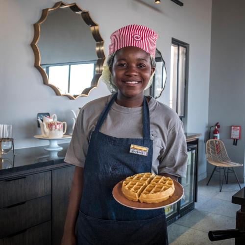 a woman in a kitchen holding a plate of waffles at The Desert Grace in Solitaire