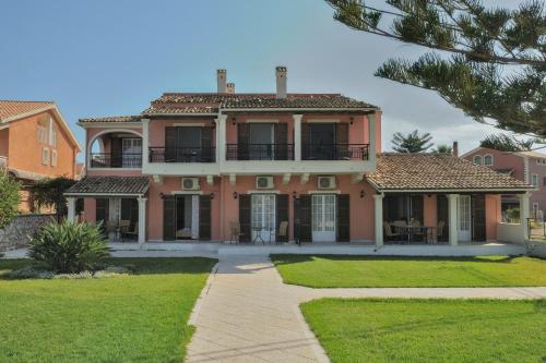 a large pink house with a pathway in front of it at Kalamionas Studios & Apartments in Kassiopi