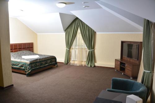 a bedroom with a bed and a tv and a window at Tropicana Inn in Uralsk