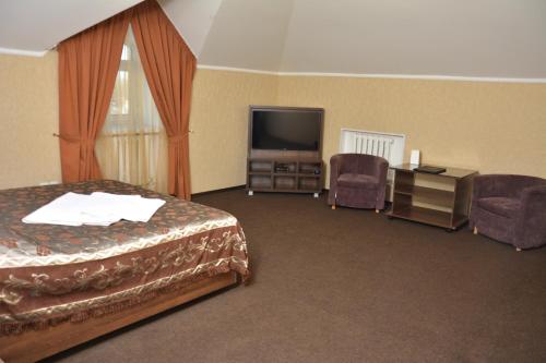 a hotel room with a bed and a tv and chairs at Tropicana Inn in Uralsk