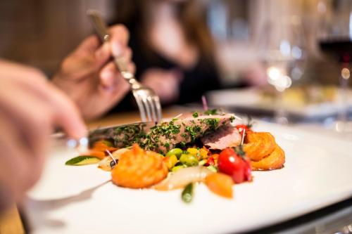 a person eating a plate of food on a table at Meiser Design Hotel in Dinkelsbühl