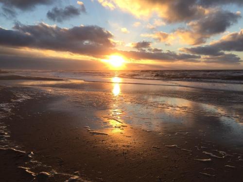 a sunset on a beach with the ocean at Badhotel Appartementen Callantsoog in Callantsoog