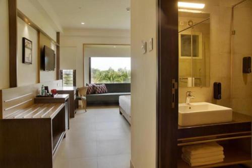 a bathroom with a tub and a sink and a living room at Purple Cloud Hotel in Devanahalli-Bangalore