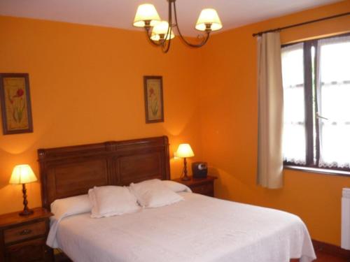 1 dormitorio con cama blanca y ventana en Apartamentos Rurales La Caramba, en Lamuño