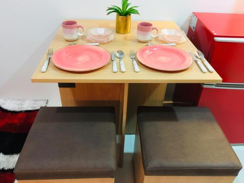 a table with pink plates and utensils on it at Cityscape Residences 1102 in Bacolod