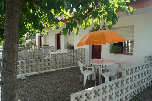 a table and chairs with an orange umbrella on a fence at Camping Cambrils Caban in Cambrils