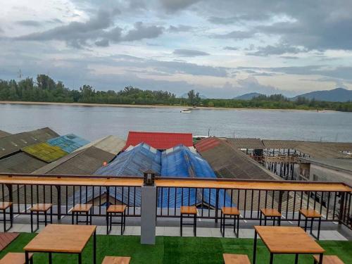 a deck with tables and chairs next to a body of water at Lanta Chaolay in Ko Lanta